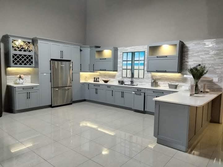Gray modern kitchen with stainless steel appliances, white countertops, and tile flooring.