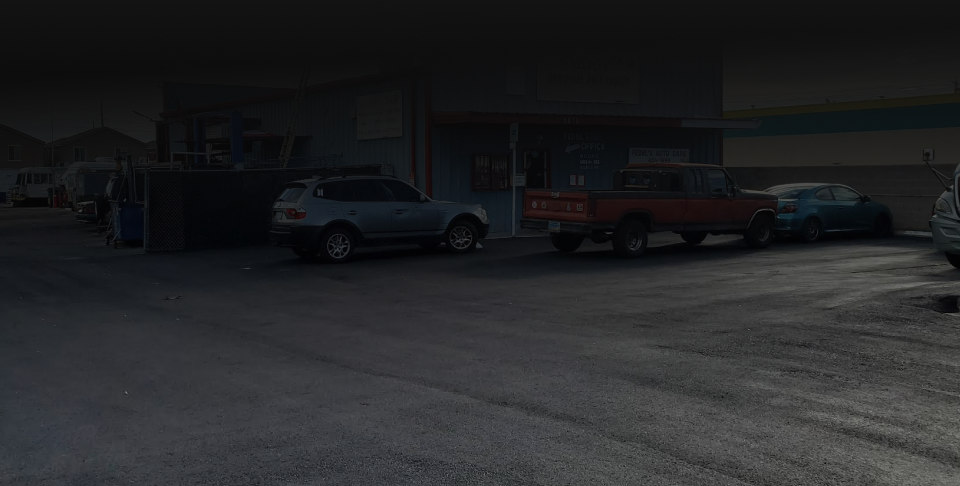 Cars parked outside a building, including a silver SUV, red truck, and blue car. | Fedel's Auto Care