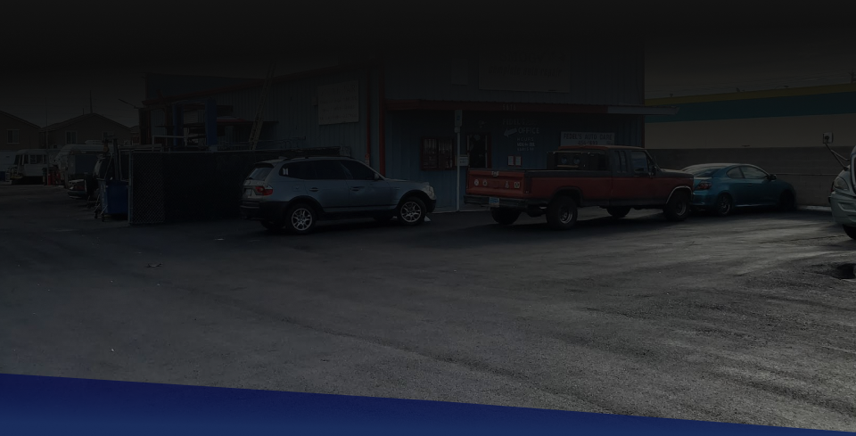 Cars parked outside a building, including a silver SUV, red truck, and blue car. | Fedel's Auto Care