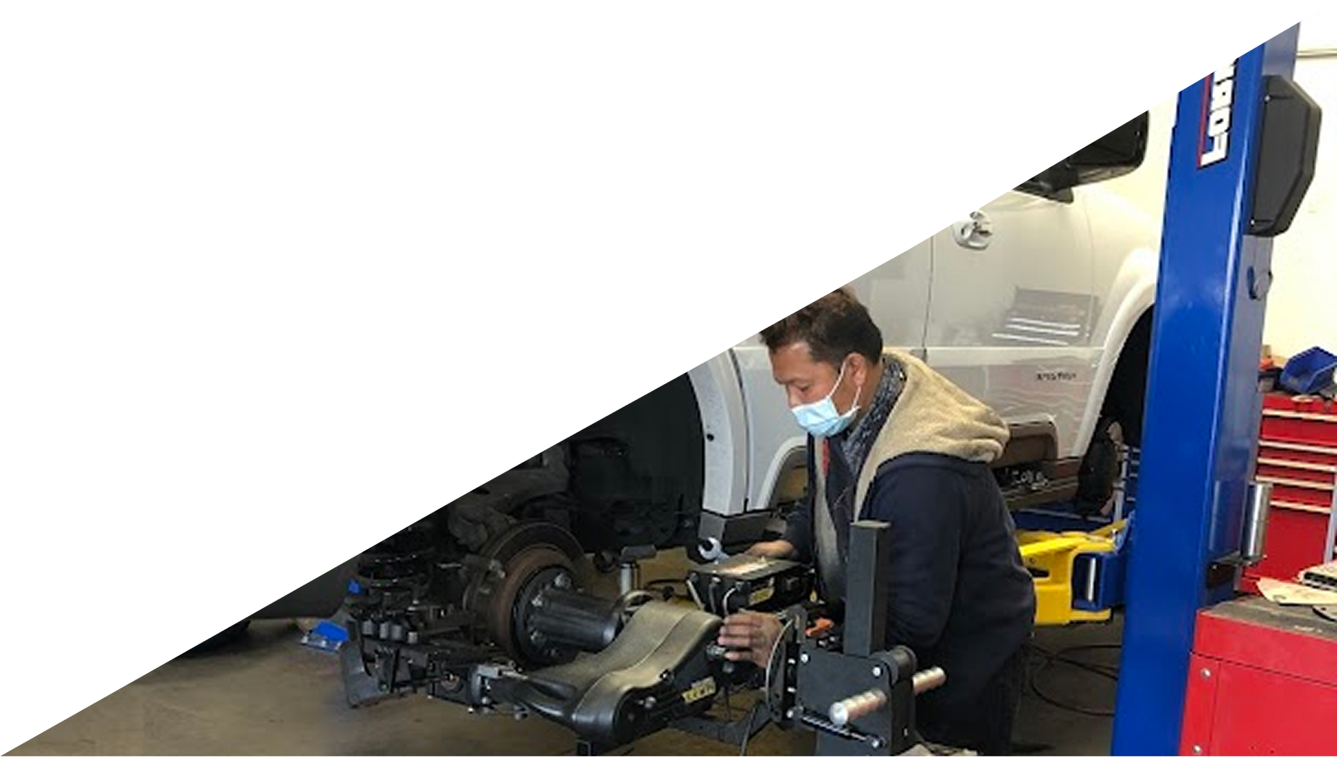 Mechanic in face mask working on car at a repair shop, using equipment. | Fedel's Auto Care