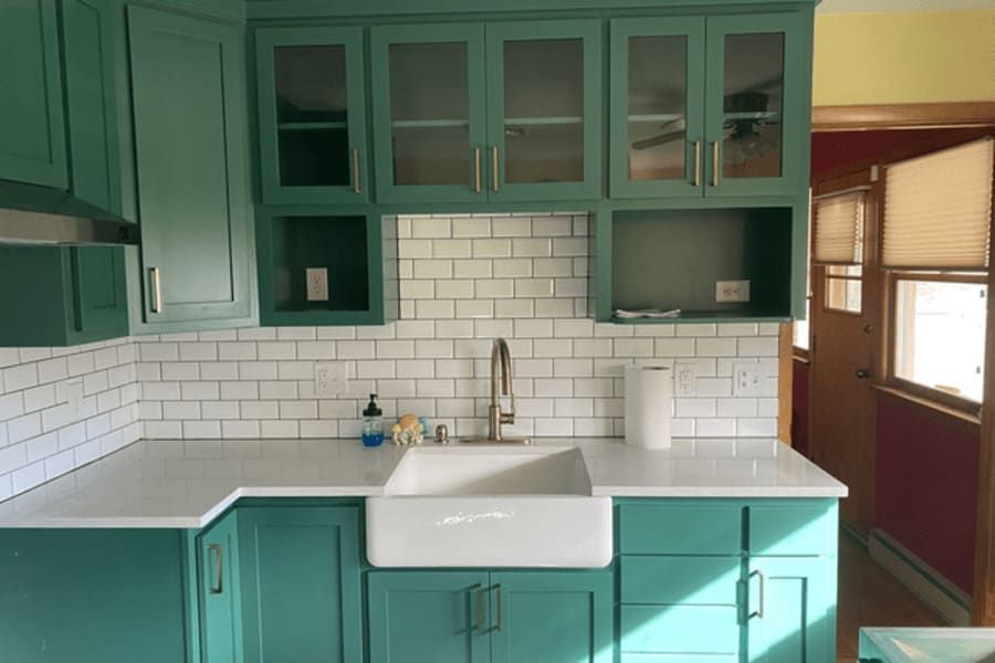 A kitchen with green cabinets and a white sink.