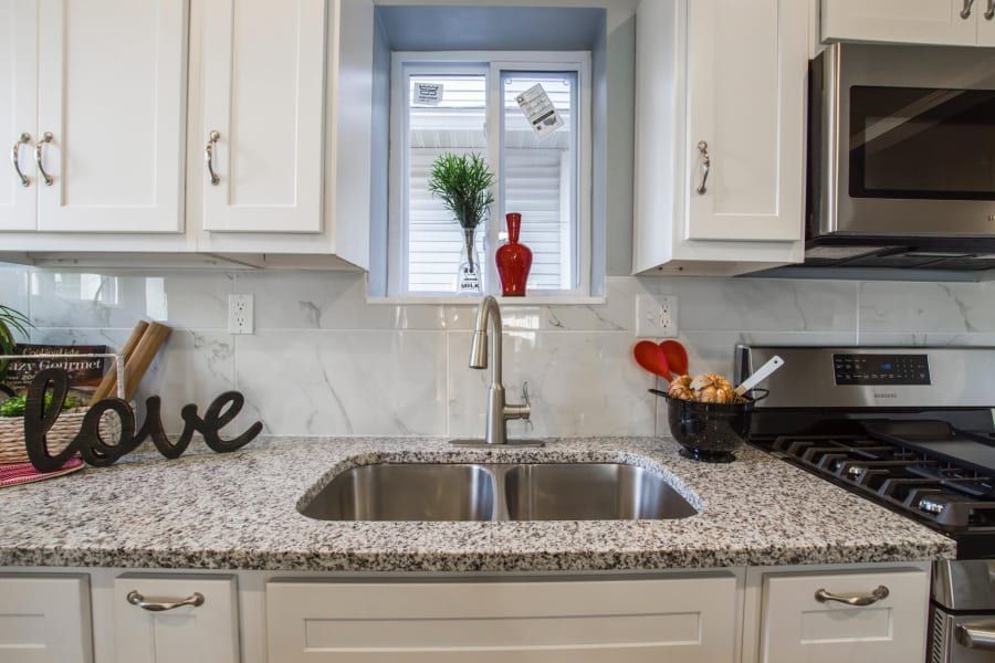 A kitchen with a sink , stove , microwave and a sign that says `` love ''.