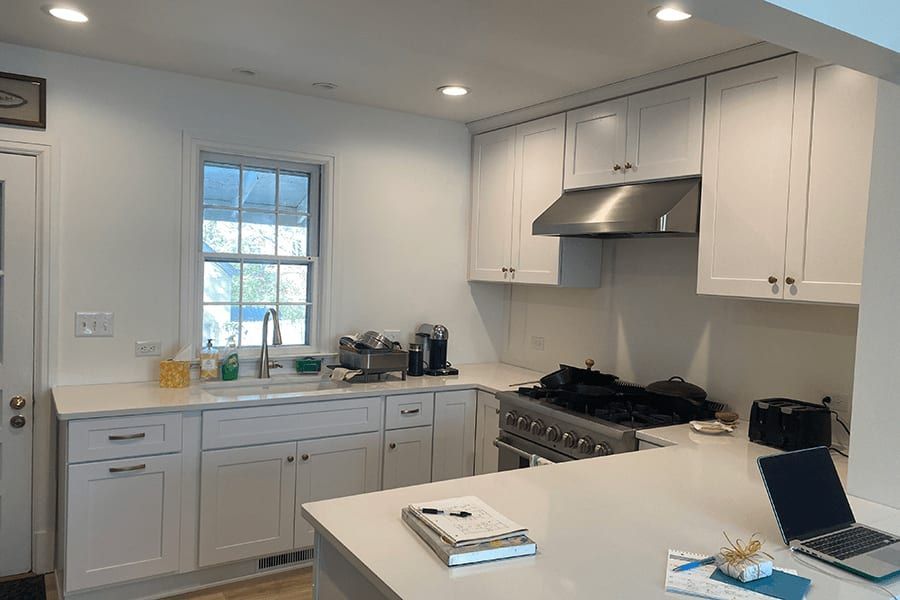 A kitchen with white cabinets and a laptop on the counter.