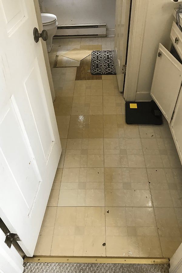 A bathroom with a tiled floor and a toilet.