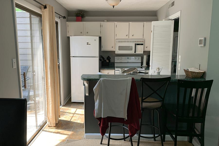 A kitchen with a refrigerator , microwave , sink , and chairs.
