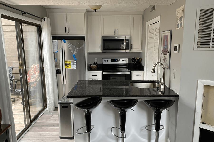 A kitchen with white cabinets , stainless steel appliances , a sink , and a refrigerator.