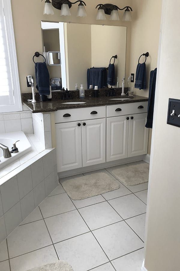 A bathroom with two sinks , a tub , and a mirror.