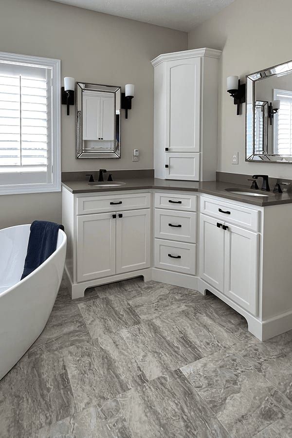 A bathroom with a tub , sink , mirror and cabinets.