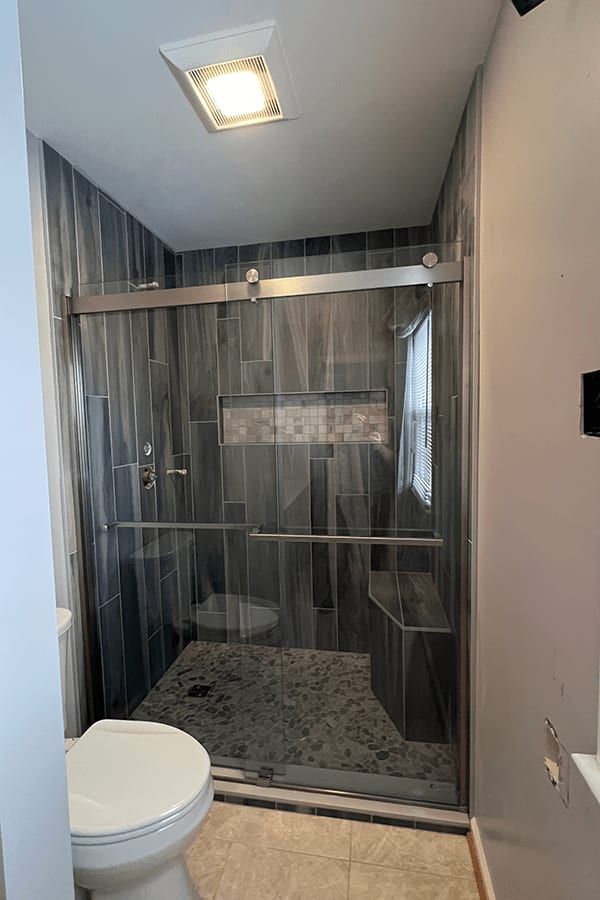 A bathroom with a toilet and a shower with a sliding glass door.