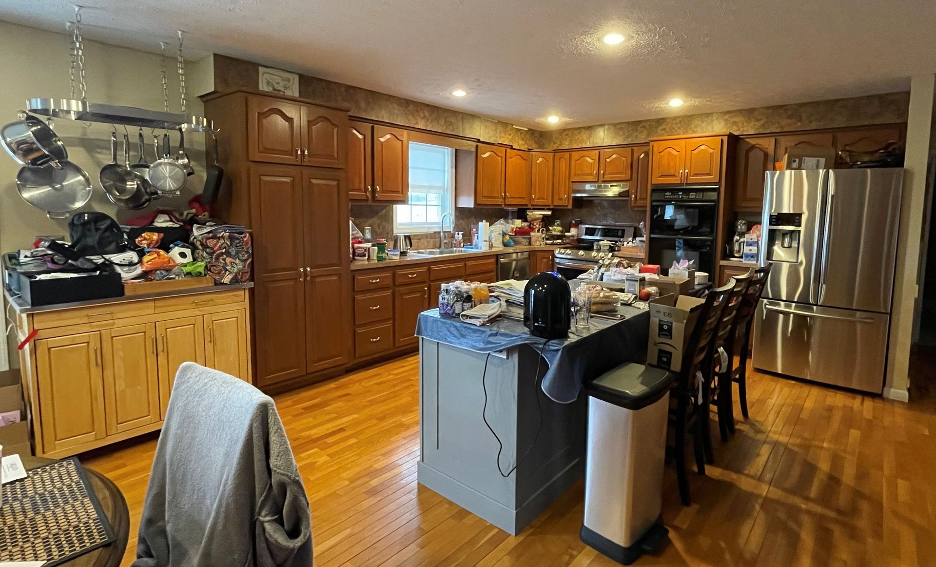 A kitchen with a refrigerator , microwave , sink , and chairs.