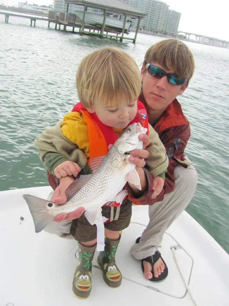 A man and a little boy holding a fish on a boat