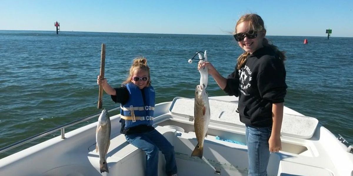 Two girls are holding fish on a boat in the ocean.