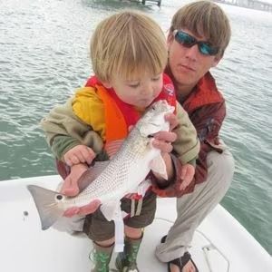 A man and a child are holding a fish on a boat.