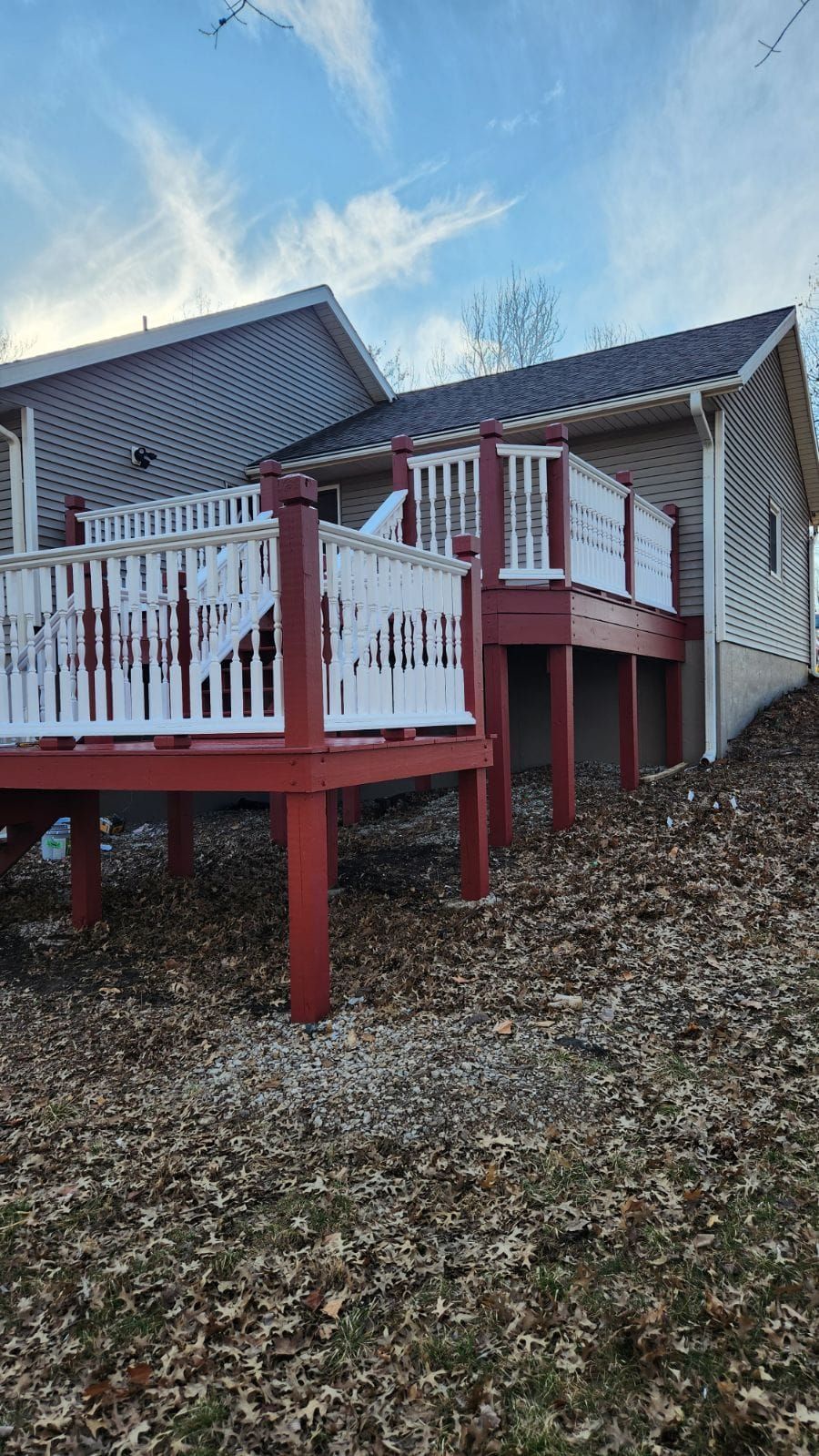 A red deck with white railings is in front of a house.