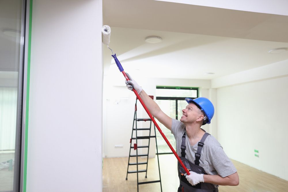 A man is painting a wall with a paint roller.