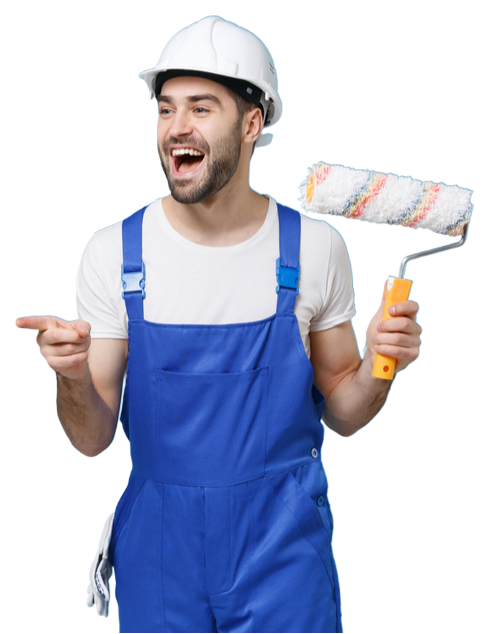 A man wearing overalls and a hard hat is holding a paint roller and pointing.