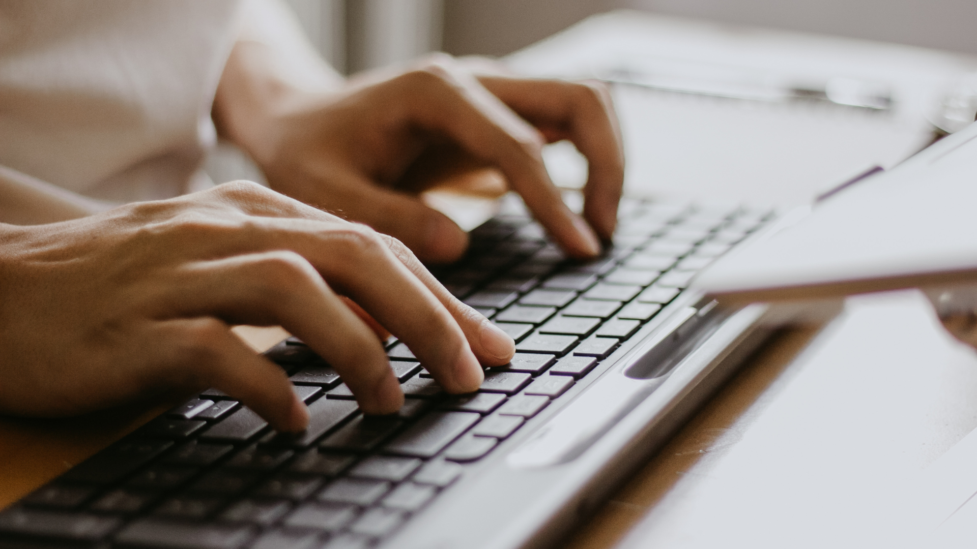 A person is typing on a laptop keyboard.