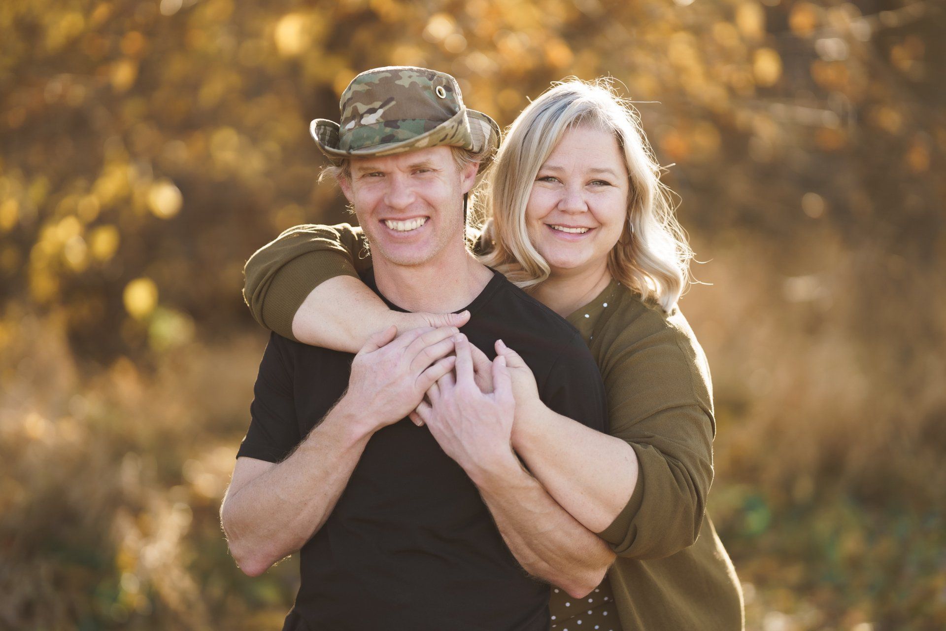 A man and a woman are hugging each other in a field.