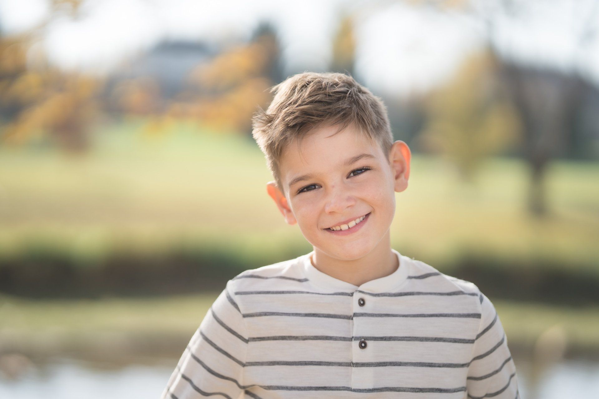 A young boy in a striped shirt is smiling for the camera.