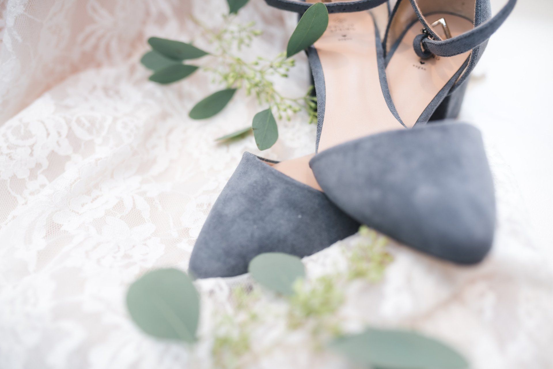 A pair of shoes sitting on top of a white lace dress.