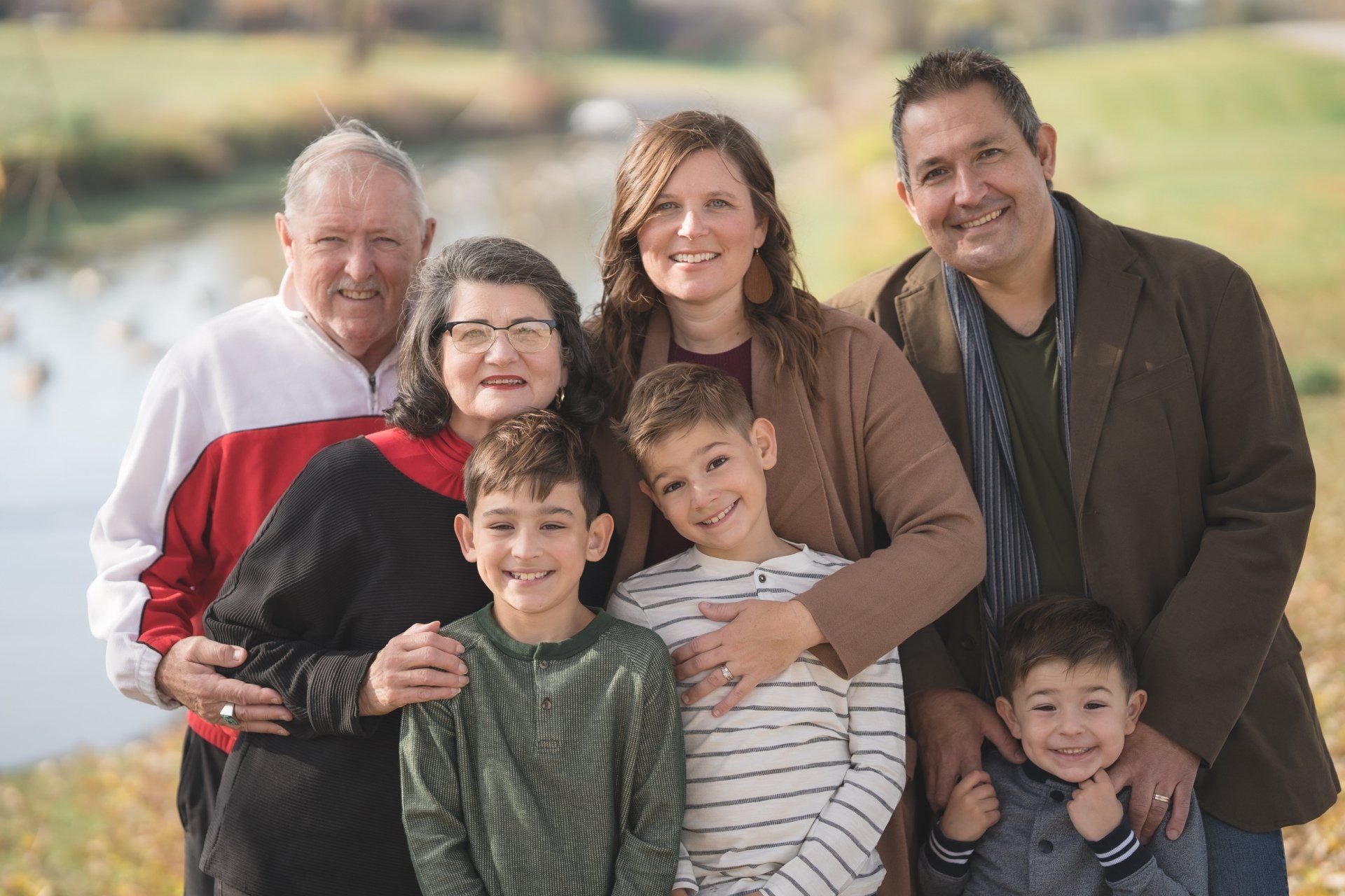 A large family posing for a picture together in front of a body of water.