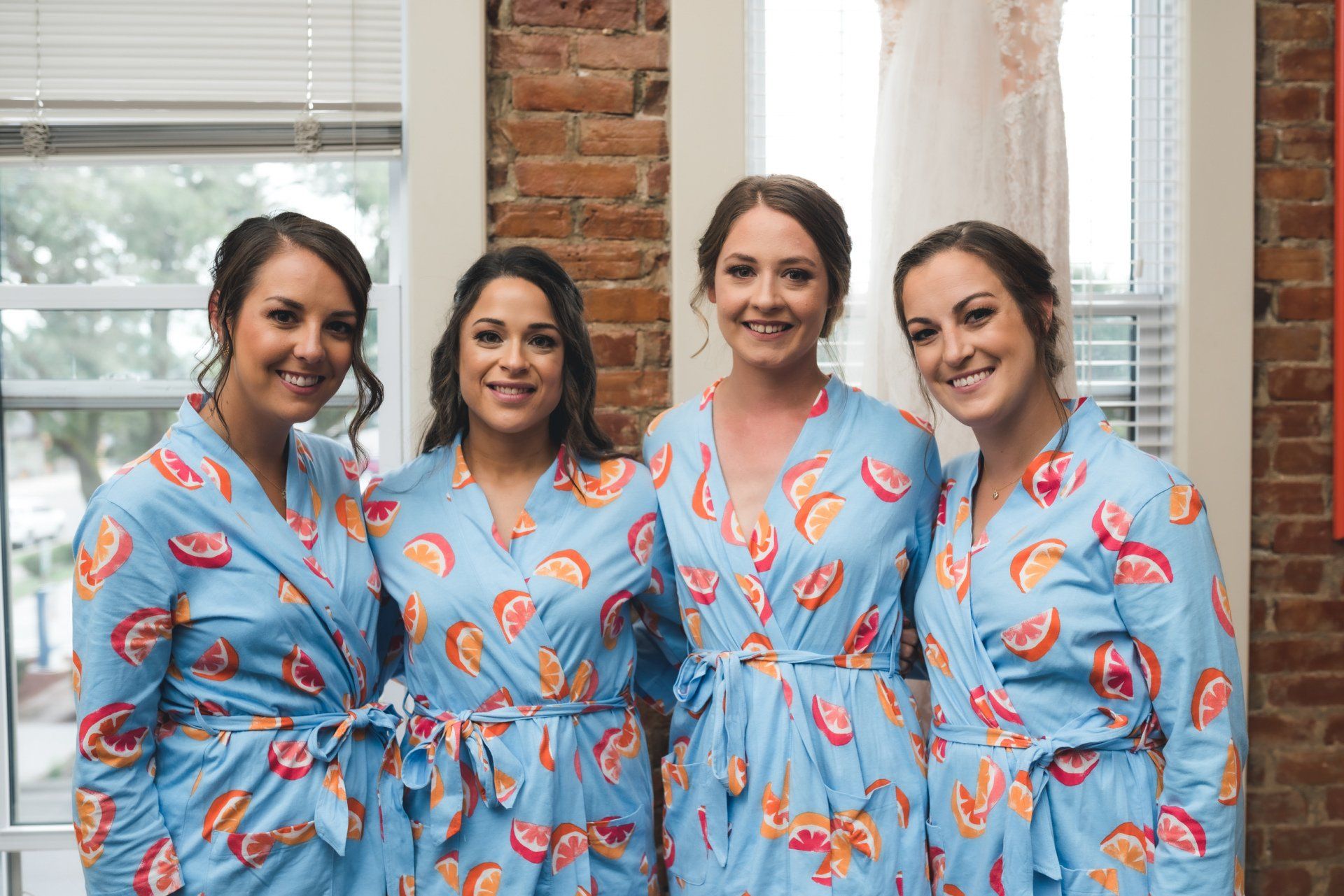 A bride and her bridesmaids are posing for a picture in robes.
