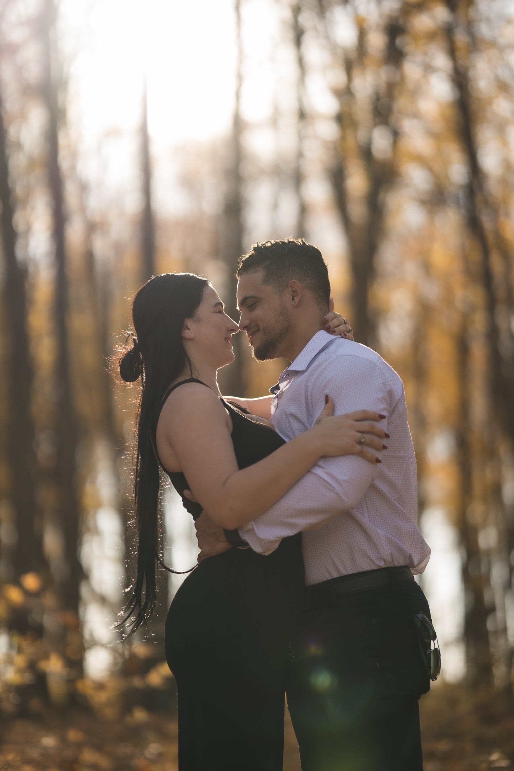 A man and a woman are kissing in the woods.