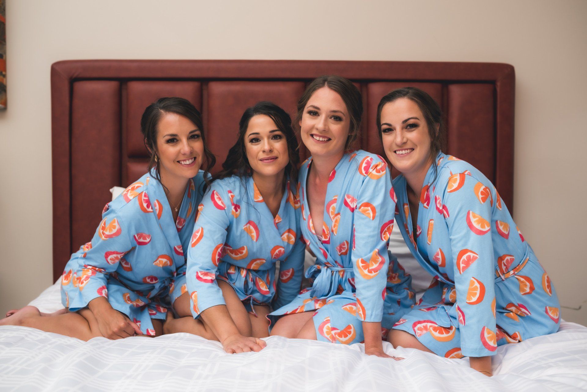 A group of women in blue robes are sitting on a bed.