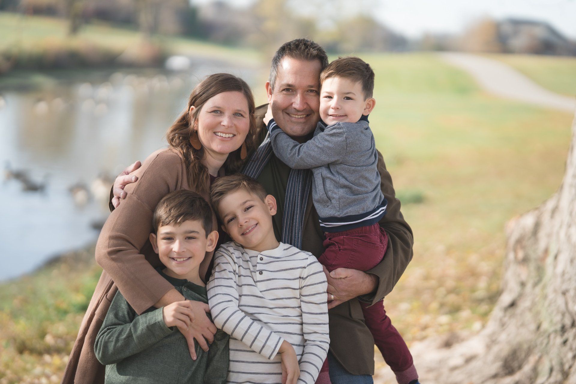 A family is posing for a picture in front of a lake.