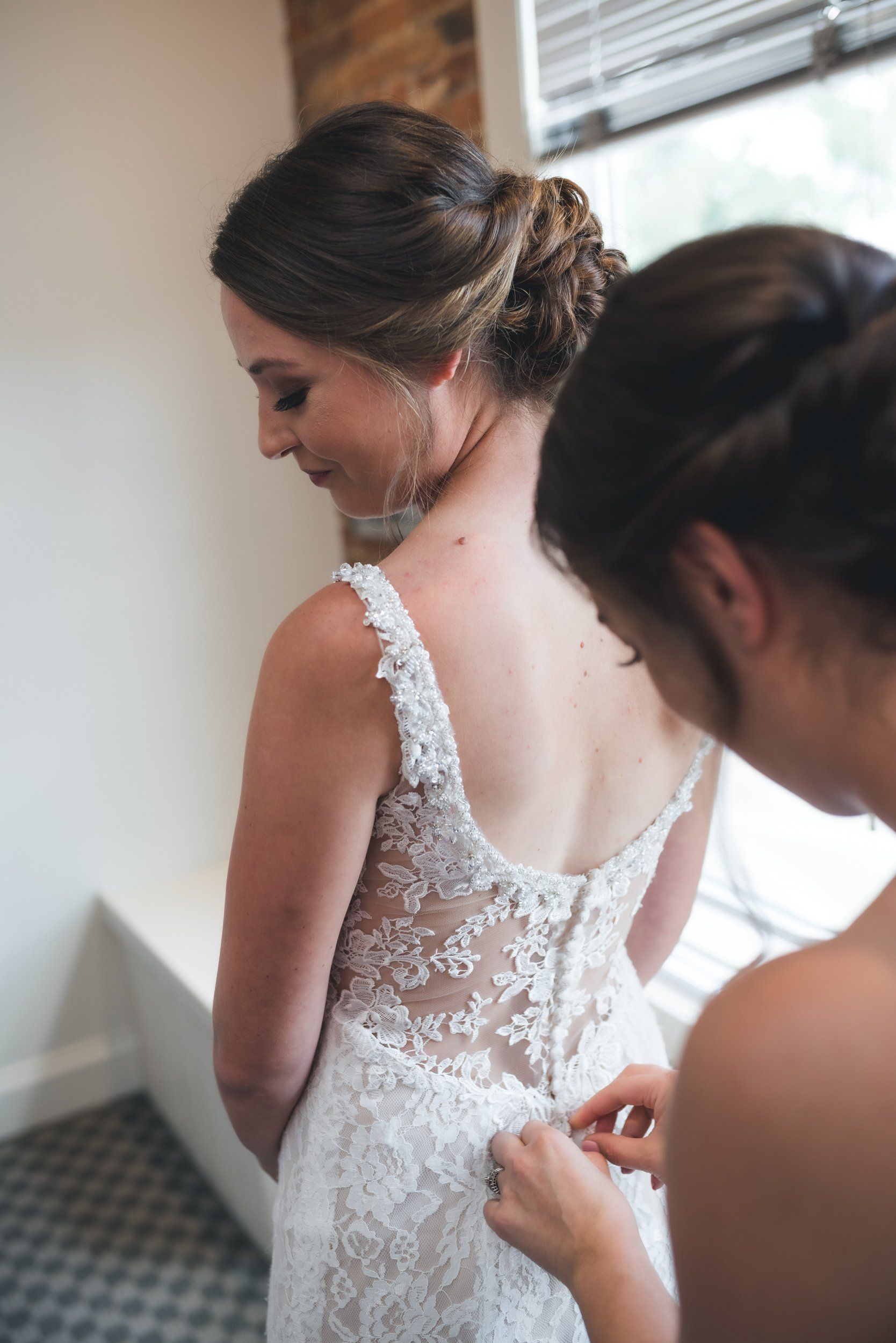 A woman is helping another woman with her wedding dress.