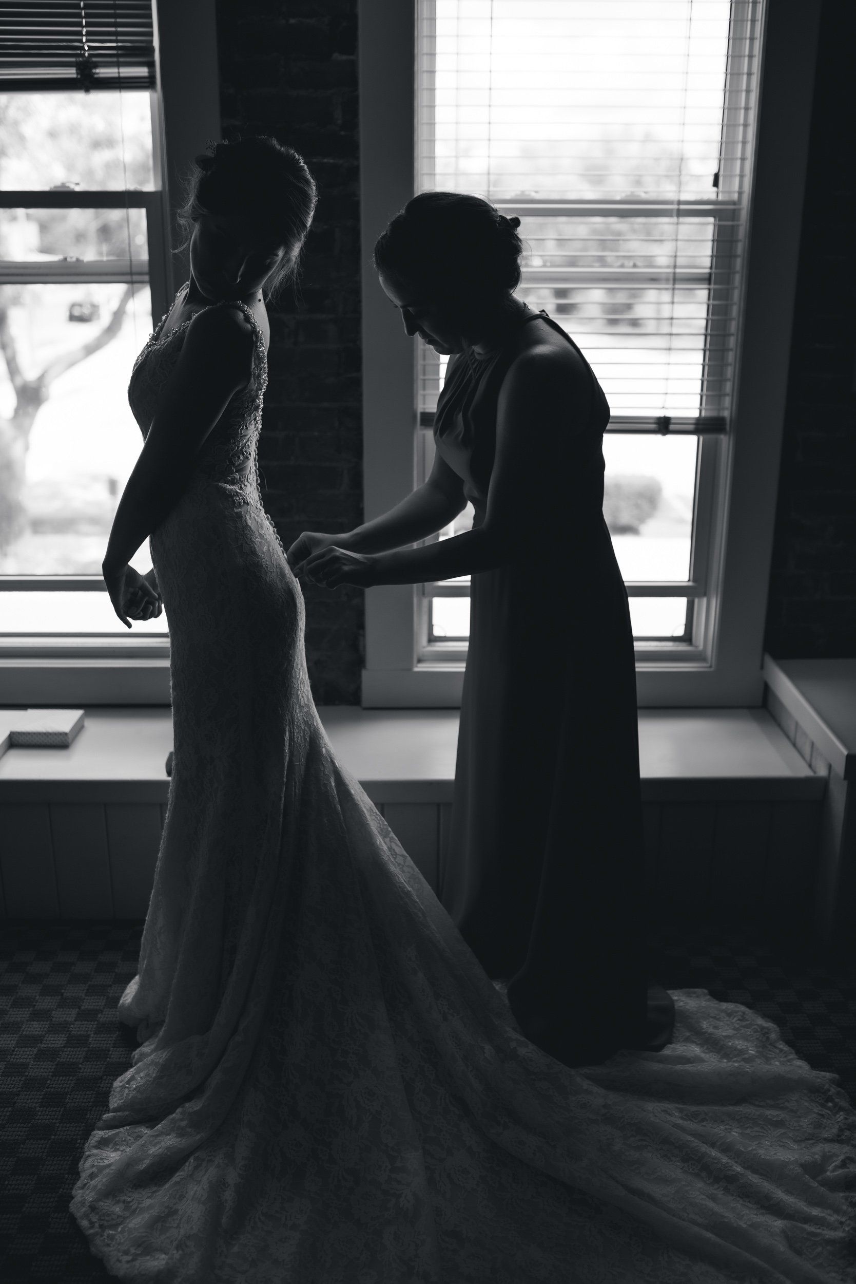 A woman is helping a bride get ready for her wedding