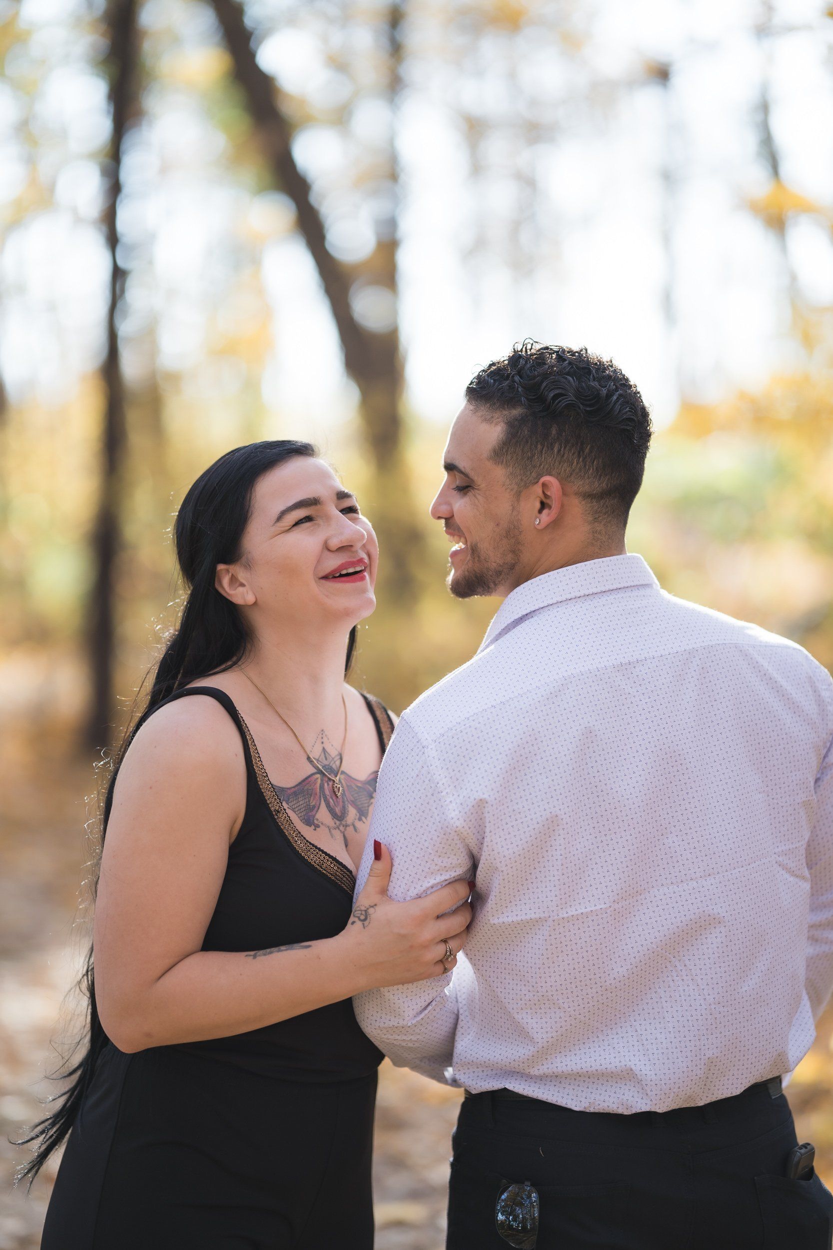 A man and a woman are standing next to each other in the woods.