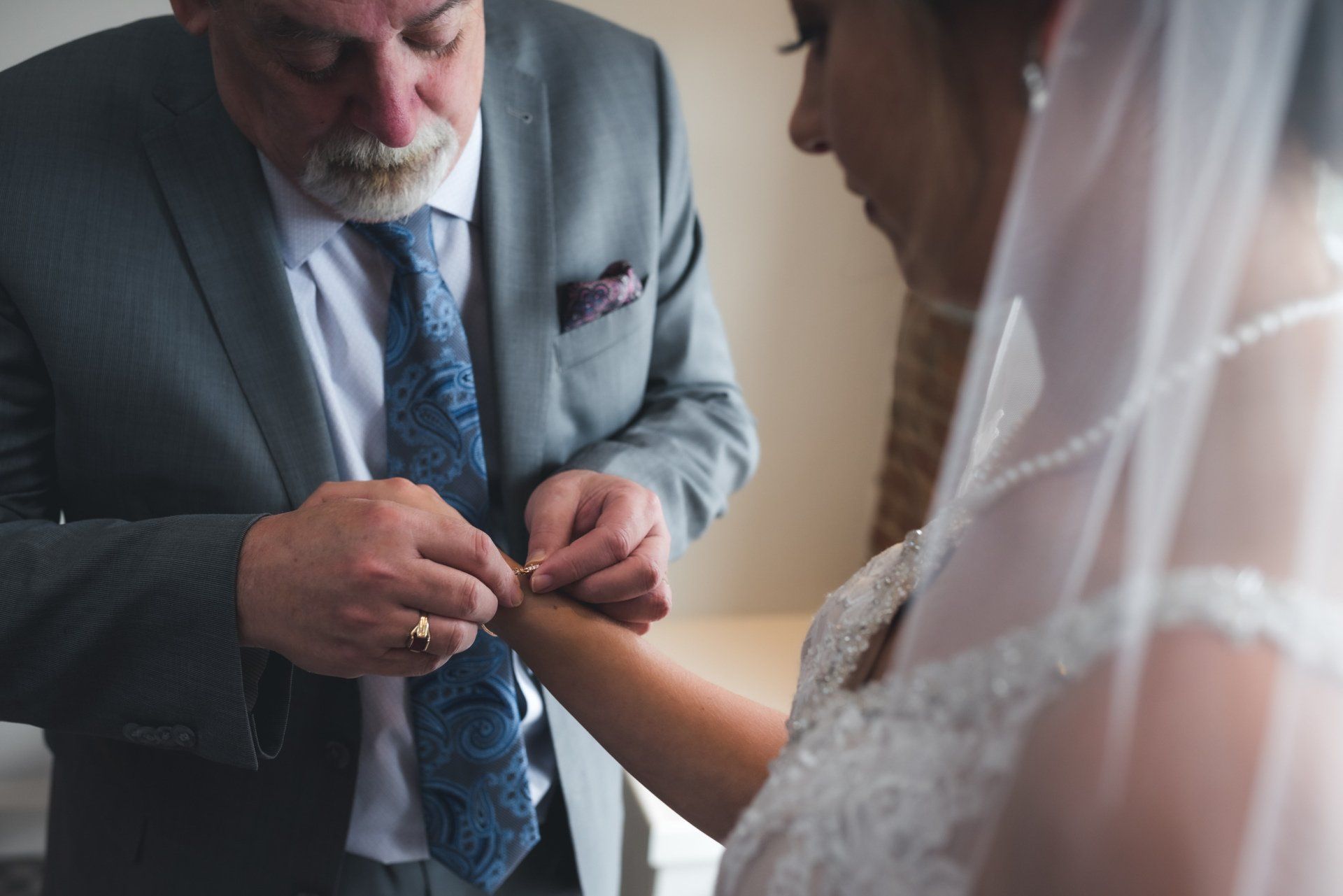A man in a suit and tie is putting a wedding ring on a woman 's wrist.