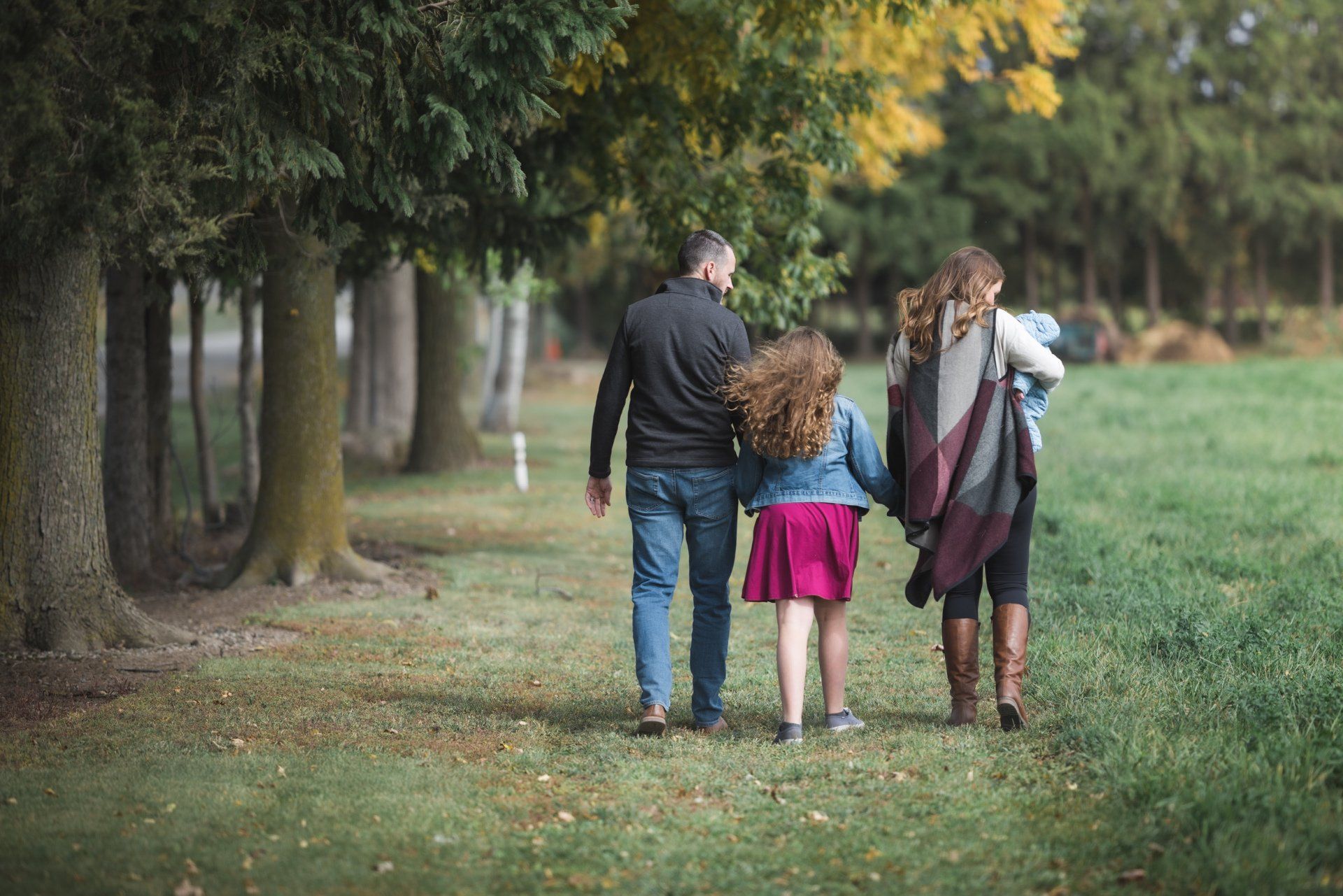 A family is walking through a park holding hands.