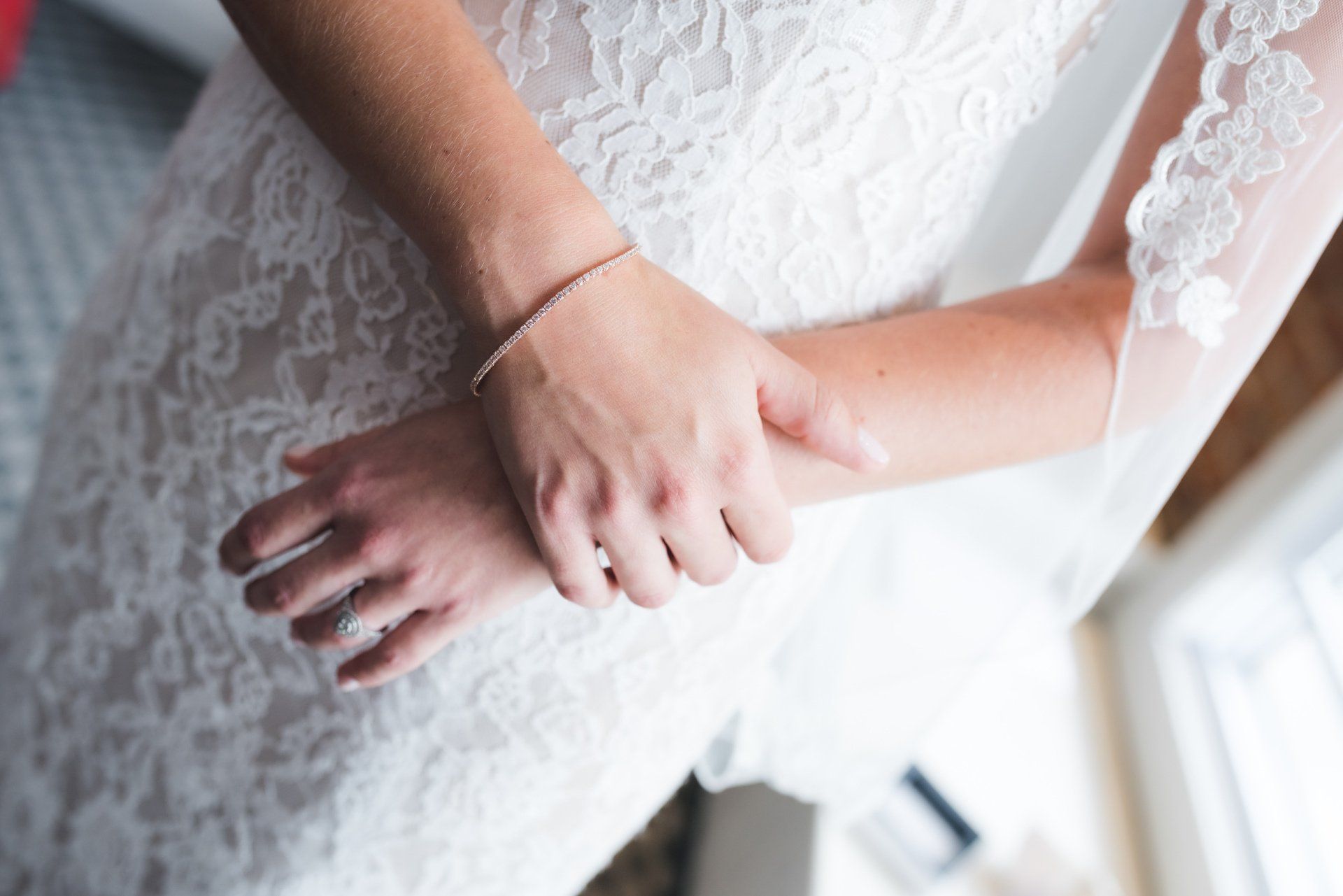A woman in a wedding dress is putting on a bracelet on her wrist.