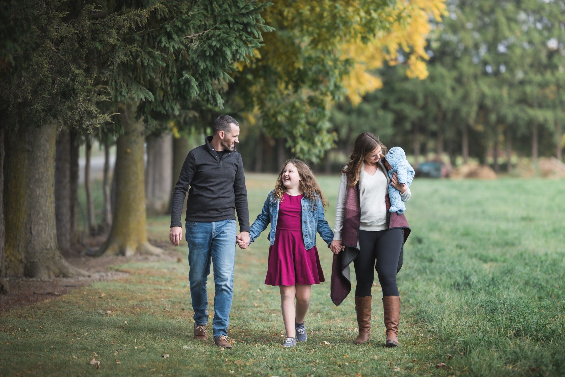 A family is walking through a park holding hands.