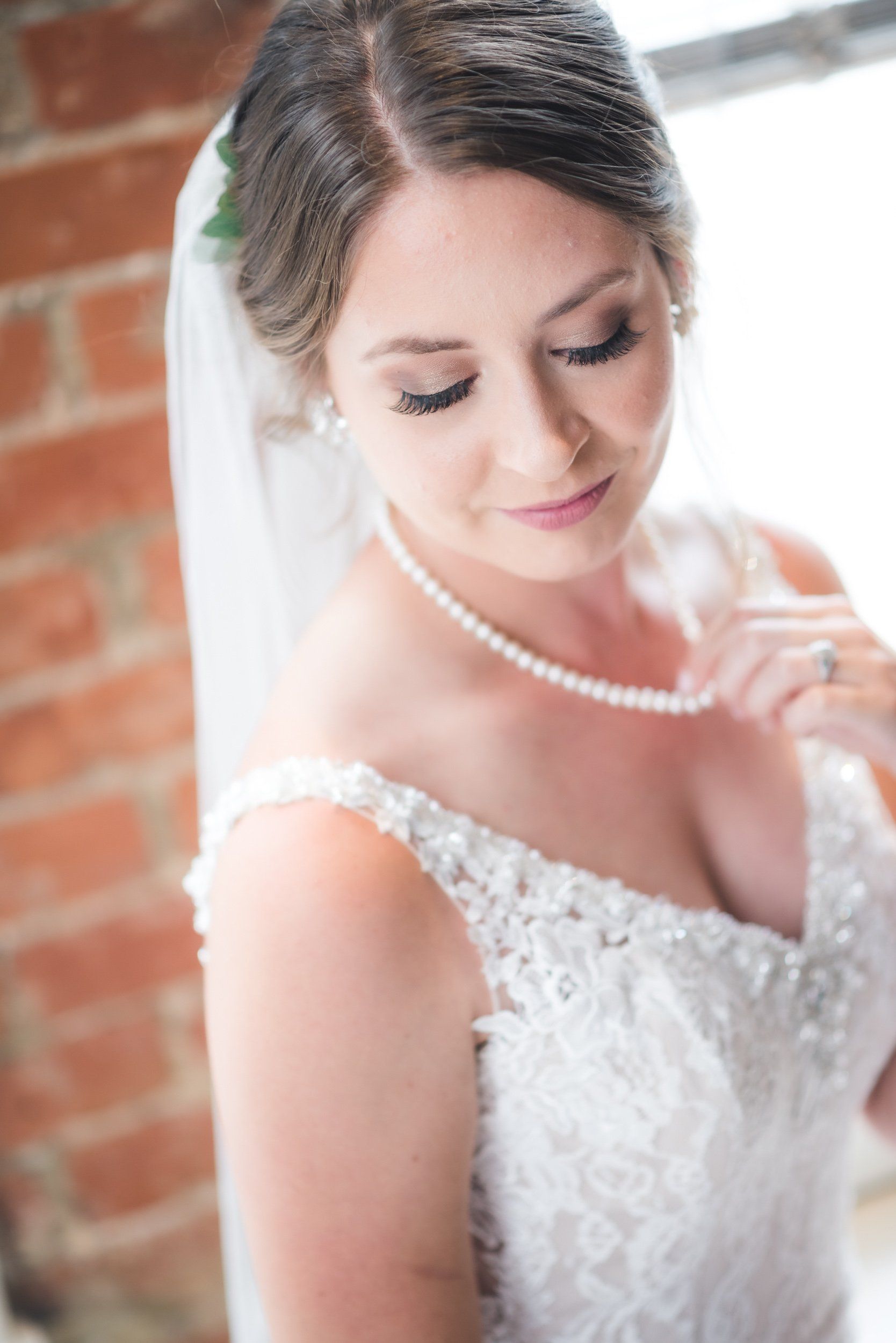 The bride is wearing a pearl necklace and a veil.