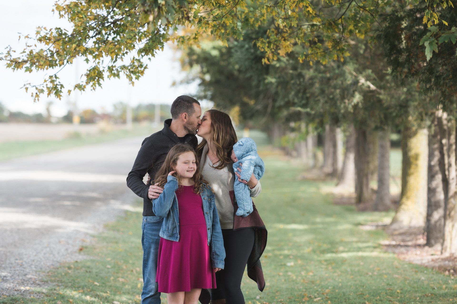 A family is standing next to each other under a tree.