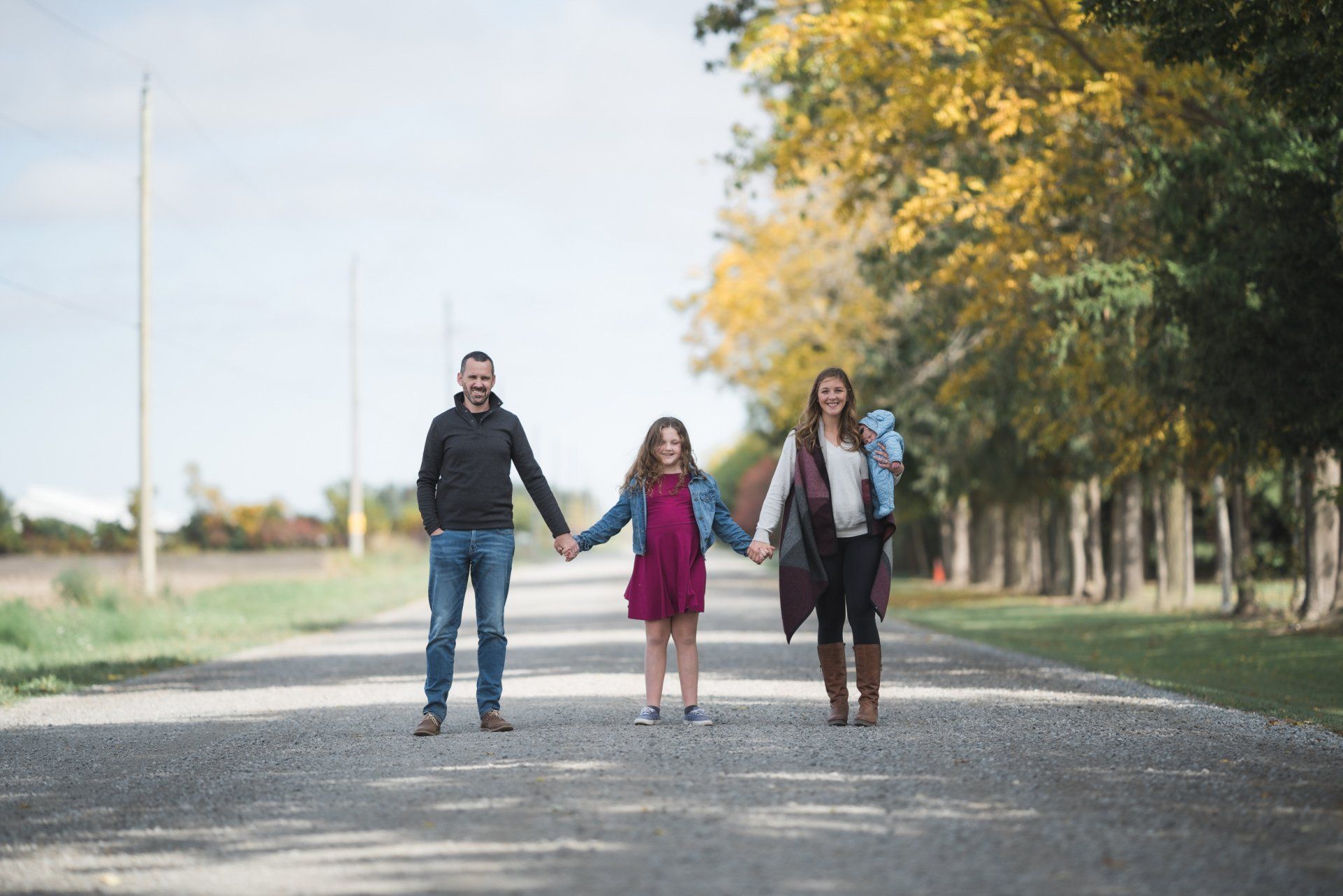A family is walking down a road holding hands.