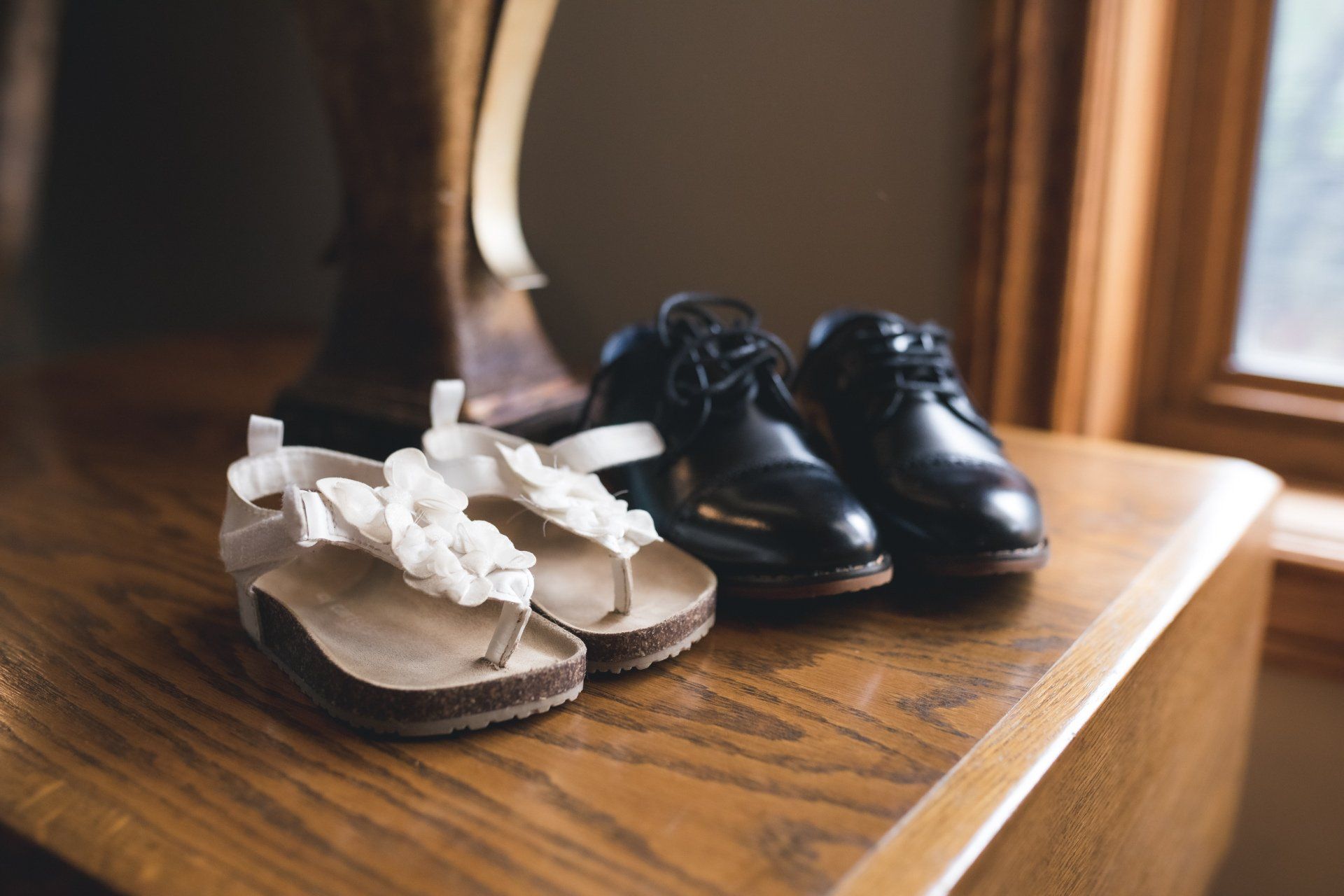 A pair of sandals and a pair of shoes are sitting on a wooden table.