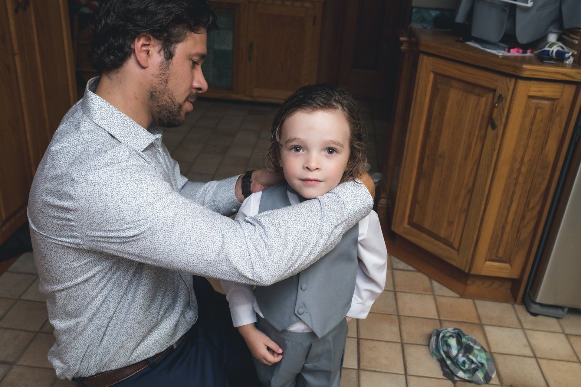 A man is helping a little boy put on a suit.