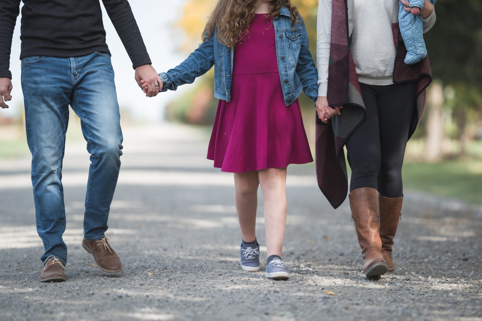 A family is walking down a road holding hands.