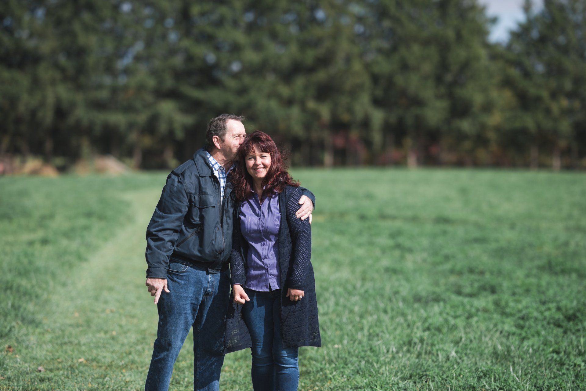 A man and a woman are standing in a grassy field.