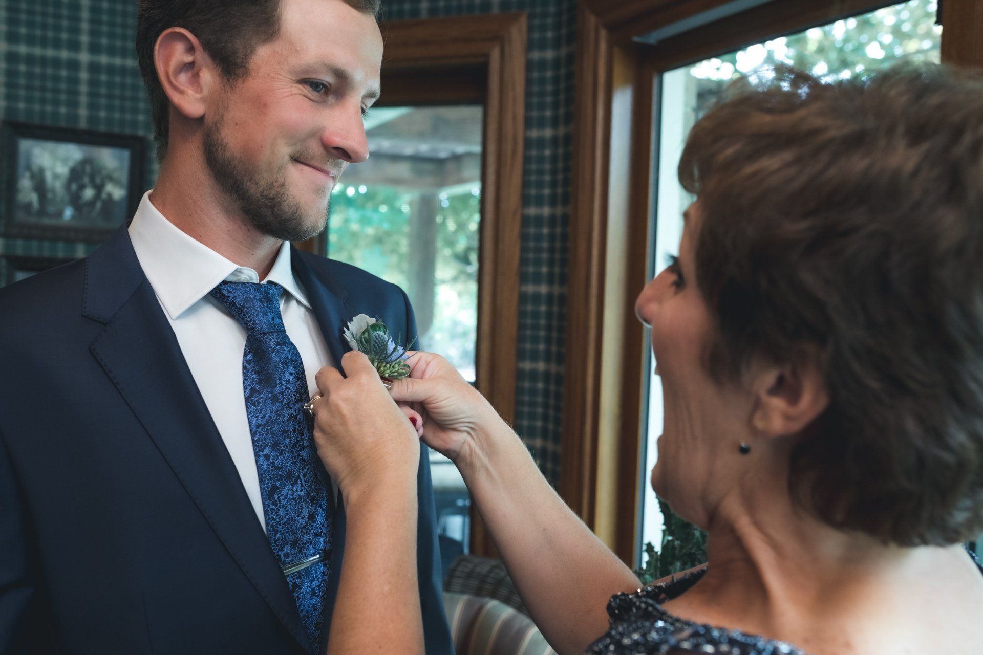 A woman is helping a man with his suit and tie.