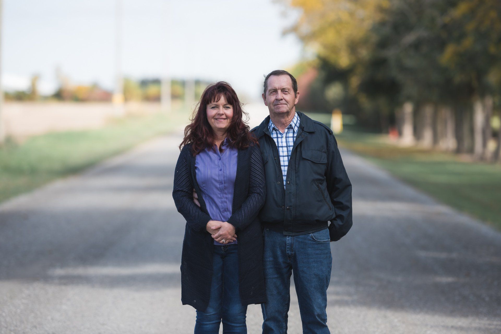 A man and a woman are standing next to each other on the side of a road.