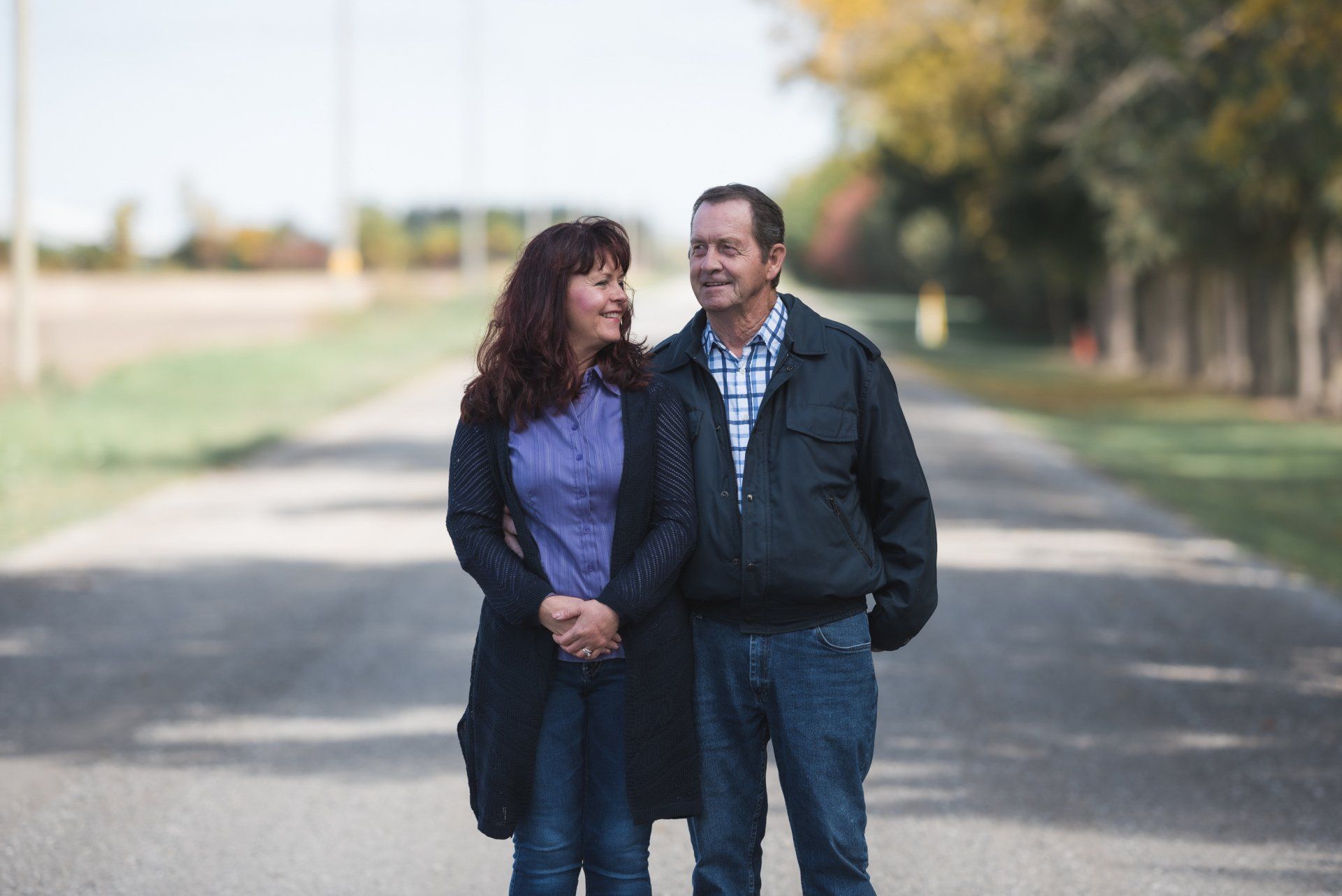 A man and a woman are standing next to each other on a road.