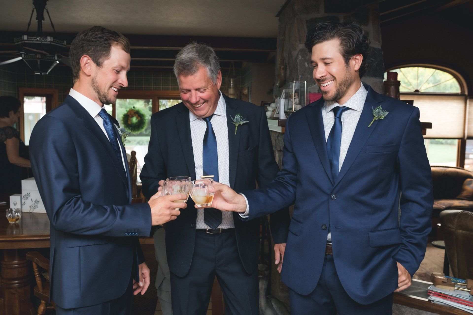Three men in suits and ties are toasting each other with drinks.