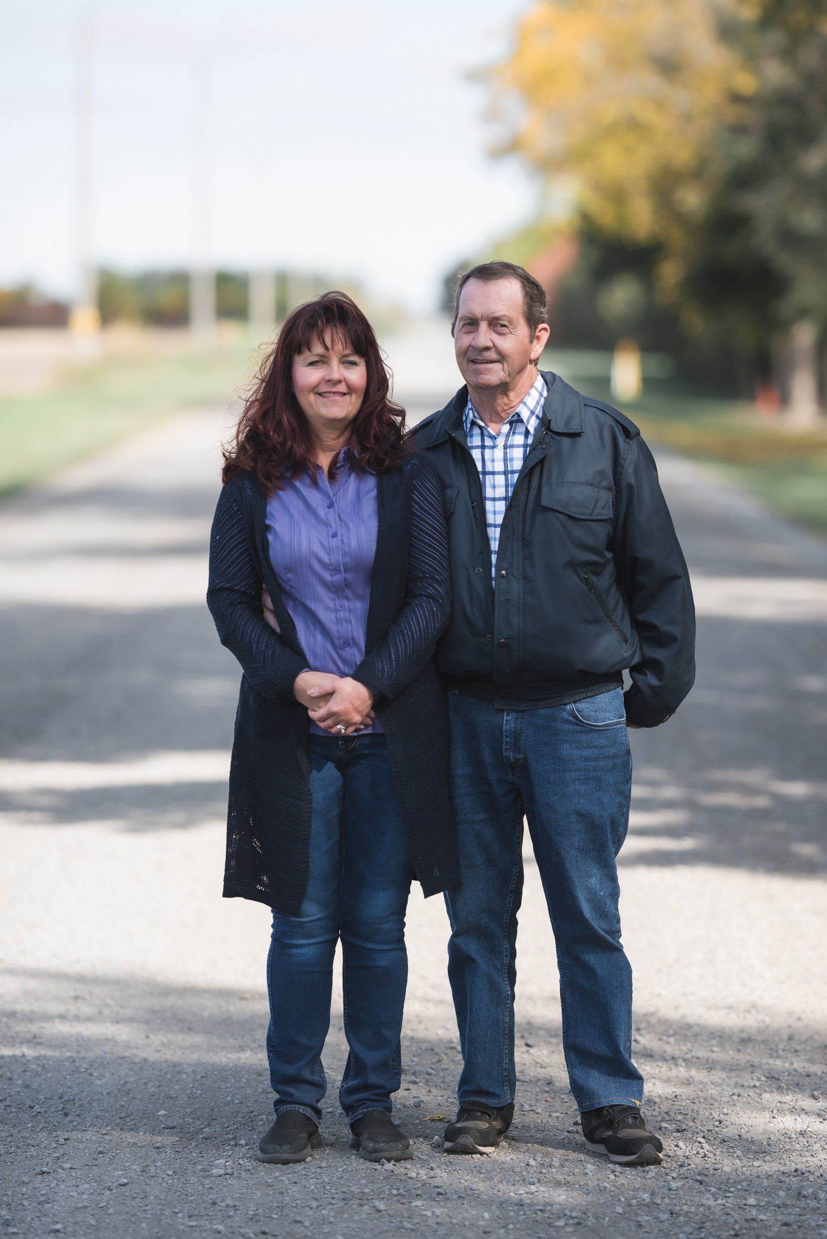 A man and a woman are standing next to each other on the side of a road.