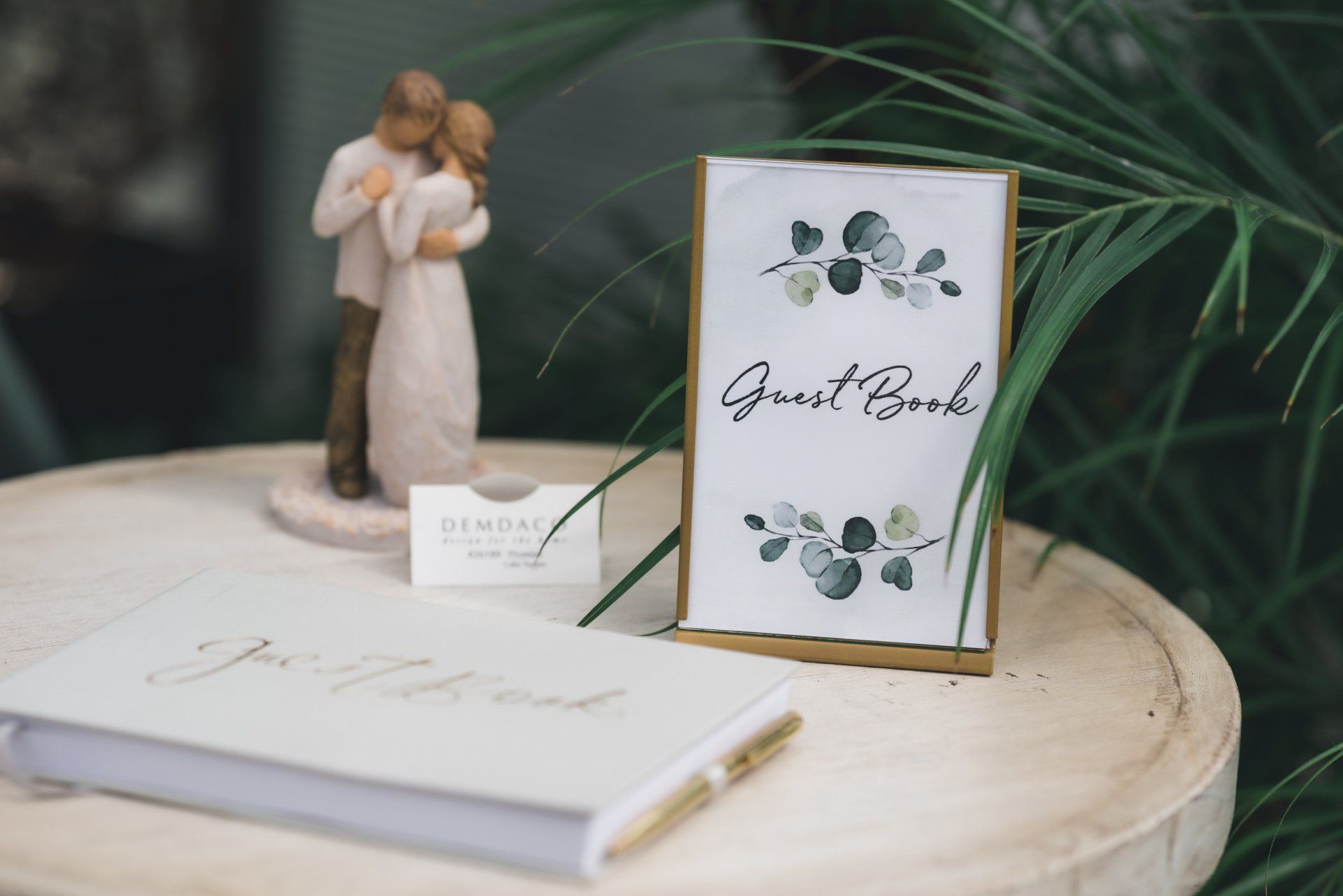 A table with a guest book , a pen , and a figurine of a bride and groom.