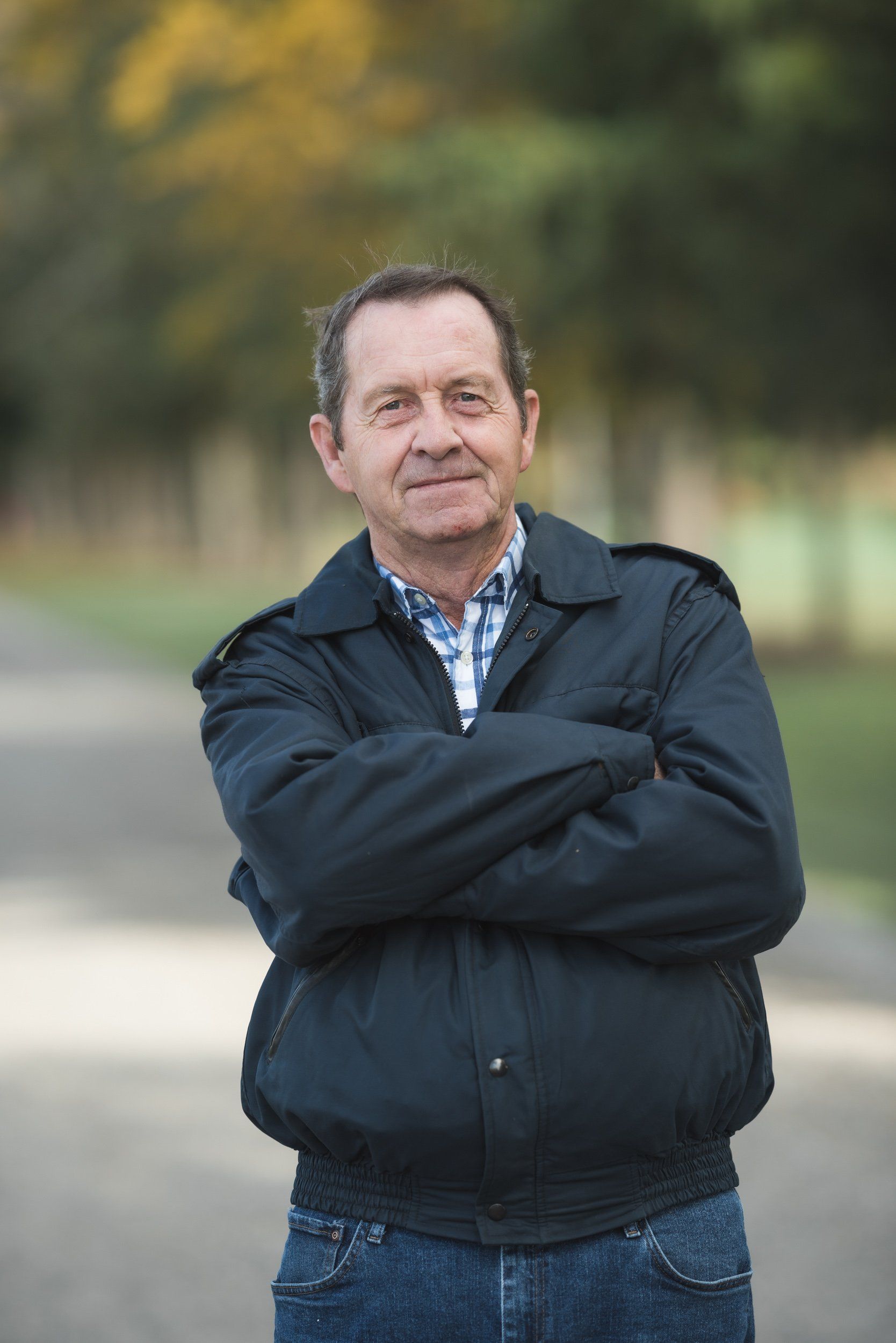 A man in a black jacket is standing with his arms crossed.